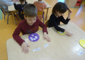 Dwoje dzieci układa wyrazy z rozsypanki literowej.